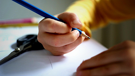 Eine Kinderhand hält einen Stift.