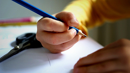 Eine Kinderhand hält einen Stift.
