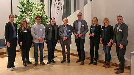 Eine Gruppe von Menschen steht in einem Sitzungssaal.