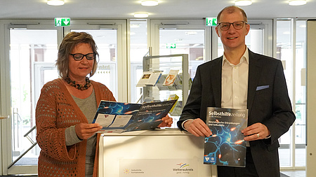 Landrat Jan Weckler und Anette Obleser (Selbsthilfe-Kontaktstelle des Wetteraukreises) präsentieren die 50. Ausgabe der Selbsthilfezeitung für die Wetterau.