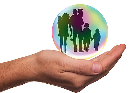 Symbolfoto: Hand hält Glaskugel, in der eine Familie abgebildet ist