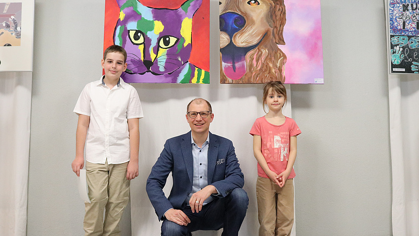 Drei Menschen stehen vor zwei Gemälden