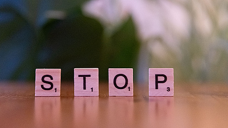 Zu lesen ist das Wort Stop, aufgestellt aus Scrabble Steinen