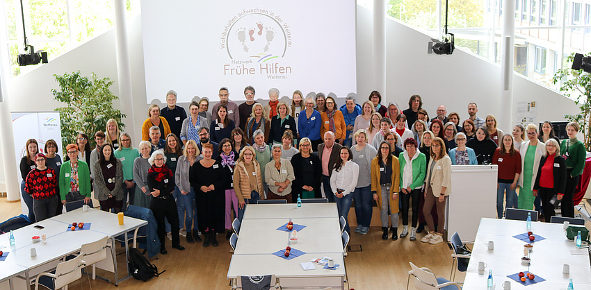 Viele Menschen stehen vor einer großen Plakatwand.