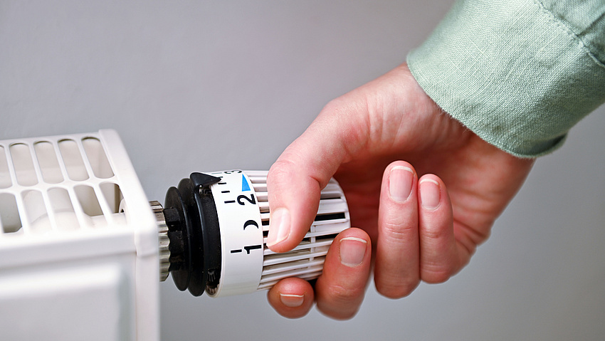 Eine Hand umgreift ein modernes Heizungsthermostat