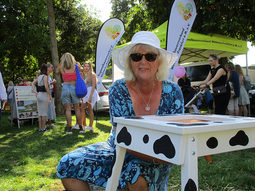 Ältere Frau melkt am Melkmodell und hat offensichtlich ihren Spaß dabei.