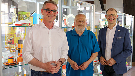 Drei Personen vor Vitrinen mit Ausstellungsstücken