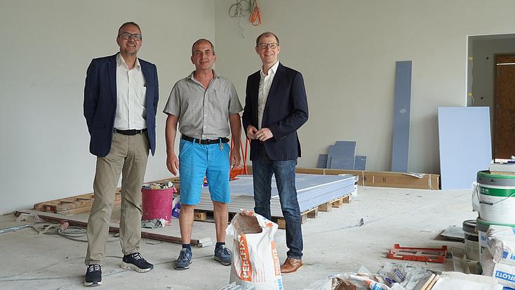 Drei Personen stehen auf einer Baustelle