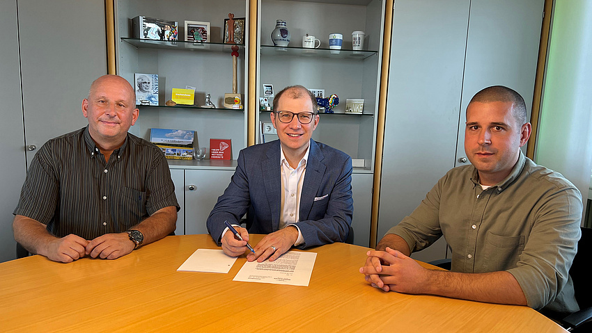 Die drei Herren sitzen am Schreibtisch des Landrats.