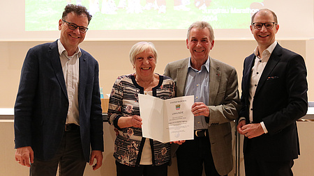 Vier Personen lächeln in die Kamera.