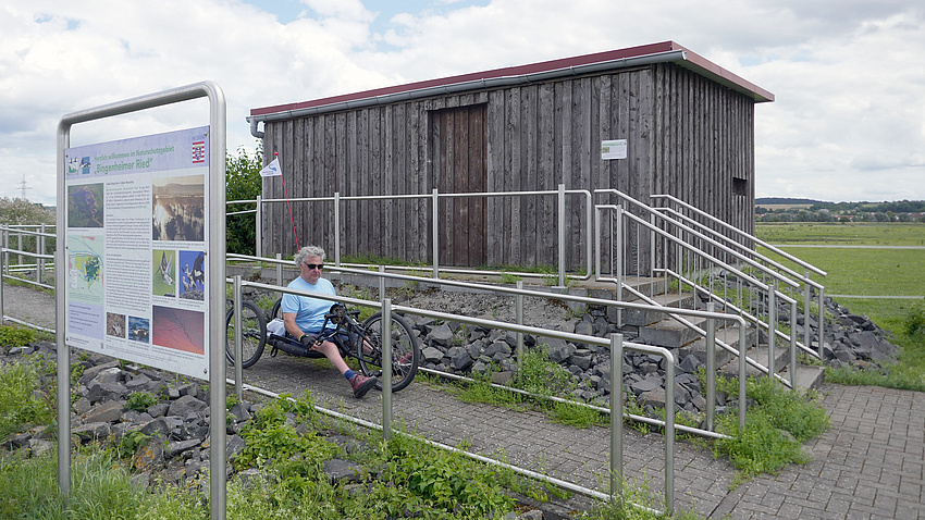 Ein Mann mit einem Handbike fährt eine Rampe hinunter.