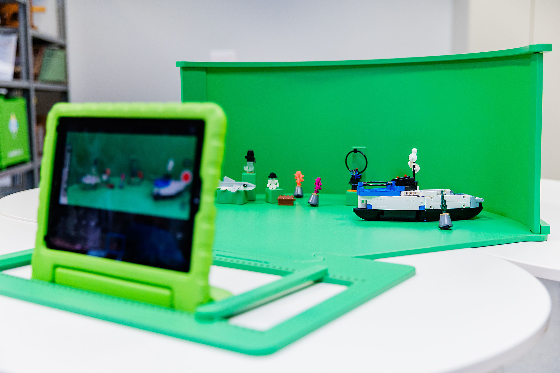 Eine Greenscreenbox mit einem Tablet und Lego Figuren auf einem Tisch.