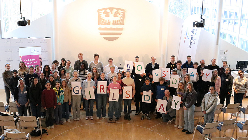 Eine große Gruppe von Mädchen und Jungen. Sie halten Schilder hoch, die die Worte "Girls' and Boys' Day" bilden.