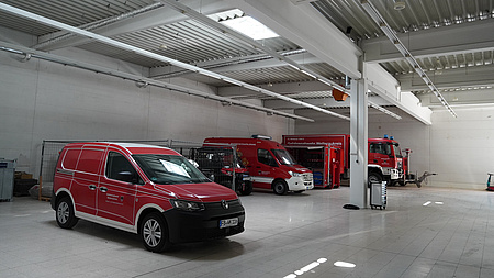 Rote Einsatzwagen in einer Halle.