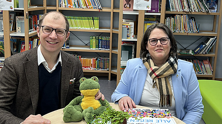 Landrat Jan Weckler und Schulleiterin Katja Bender sitzen an einem Tisch.