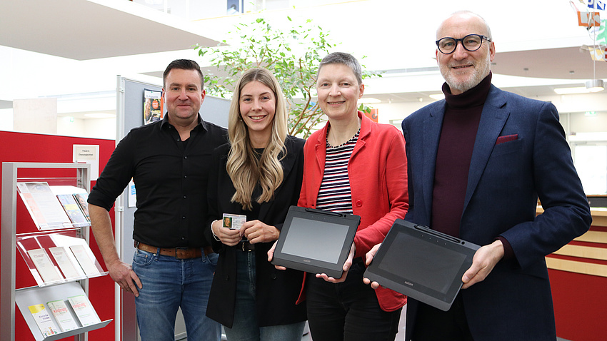 Peter Müller, Alisa Ambron, Marion Götz und Jürgen Grünbein lächeln in die Kamera. Sie halten Tablets in der Hand.