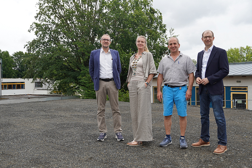 Vier Personen stehen nebeneinander und besichtigen die Baumaßnahmen an einer Schule