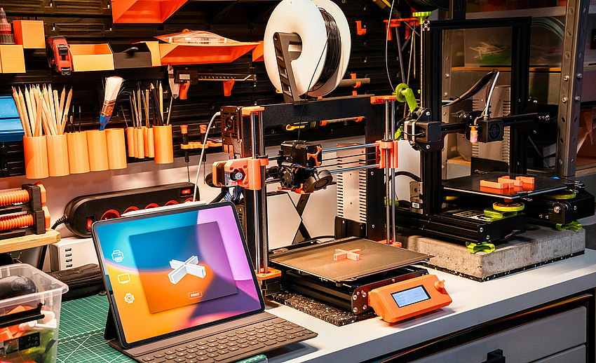 3-D Druck-Werkstatt zeigt ein 3-D Modell , das von einem daneben stehenden 3-Drucker gedruckt wird.