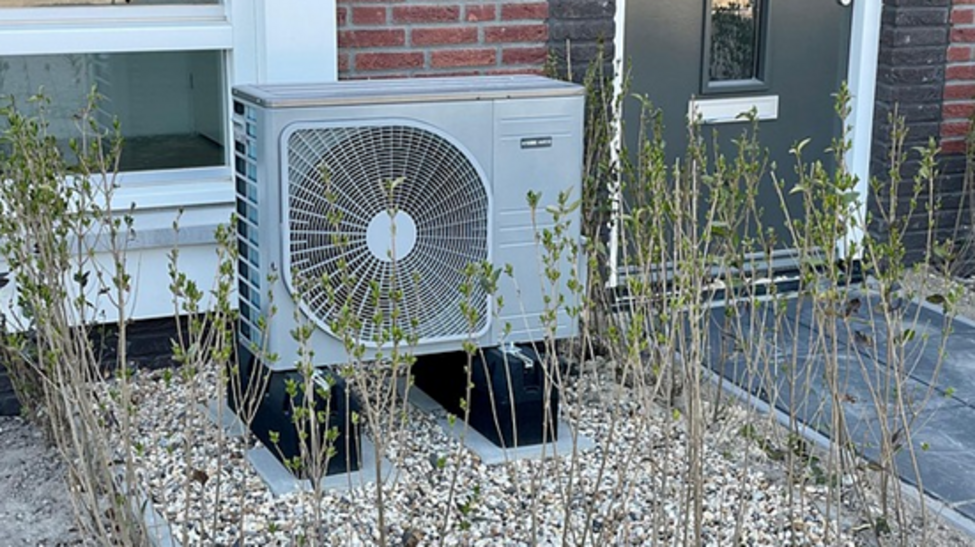 Eine Wärmepumpe vor einem Haus im Kiesbett