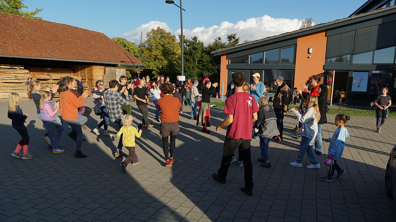 Eine Gruppe Menschen tanzt gemeinsam unter freiem Himmel