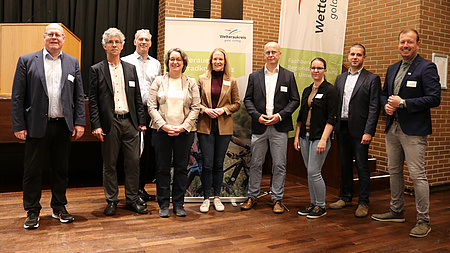 Neun Männer und Frauen stehen vor einem Aufsteller mit der Aufschrift "Wetterauer Fahrradkonferenz".
