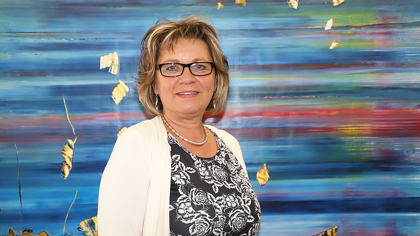 Ein Frau steht vor einem blauen Gemälde.