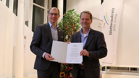 Zwei Männer halten gemeinsam eine Urkunde