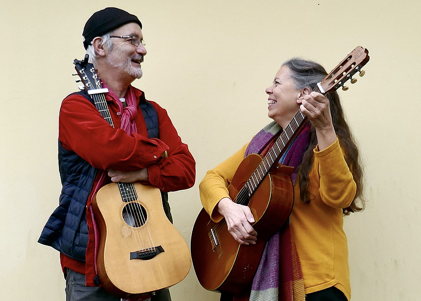 Ein Mann und eine Frau mit Gitarren in der Hand strahlen sich an