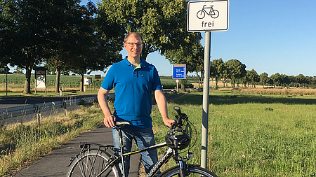 Landrat Weckler mit seinem Fahrrad vor dem Schild "Fahrrad frei"