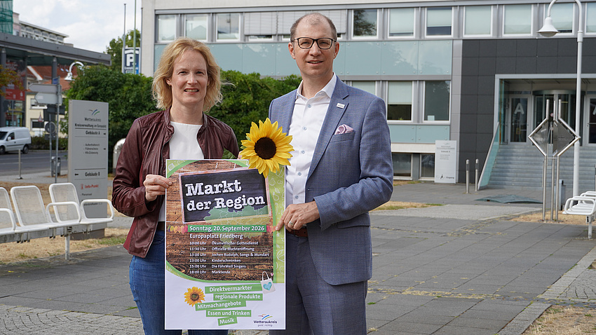 Gemeinsames Foto von Landrat und Erster Kreisbeigeordneter mit einem Plakat zum Markt der Region.