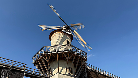 Eine Windmühle vor blauem Himmel.