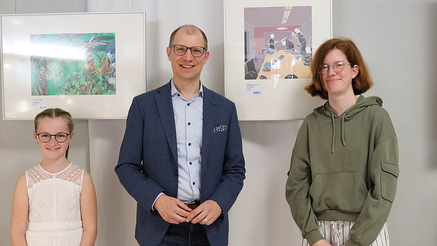 Drei Menschen stehen vor zwei Gemälden.