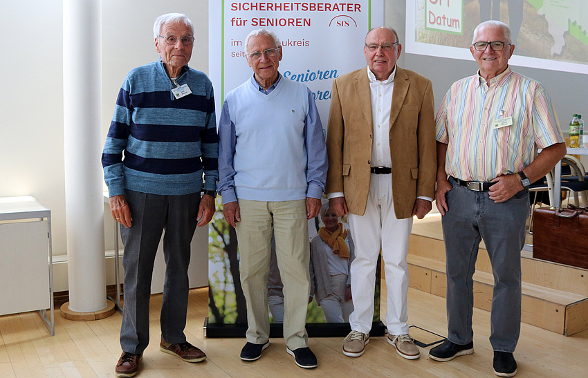 Vier Männer stehen nebeneinander und lächeln in die Kamera.