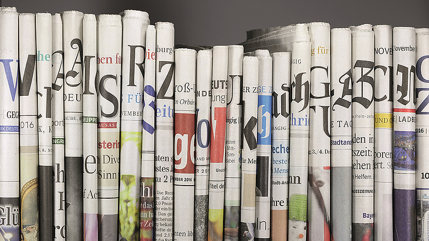 Verschiedene Tageszeitung stehend in einem Bücherregal