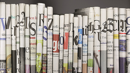 Verschiedene Tageszeitung stehend in einem Bücherregal