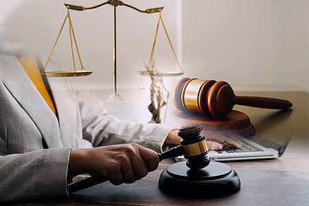 Frauenhand am Schreibtisch mit einem Richterhammer