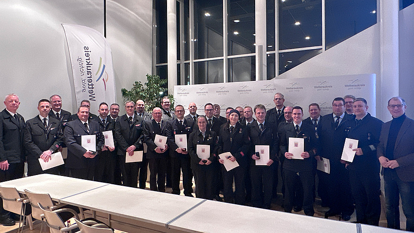 Mehrere Personen halten Urkunden in den Händen und schauen in die Kamera.