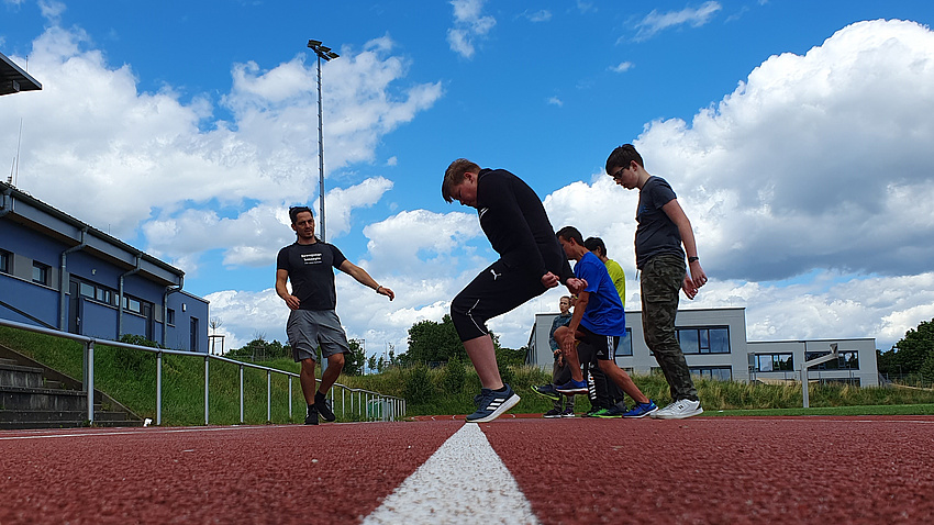 Mehrere Jugendliche hüpfen auf einer Tartanbahn.