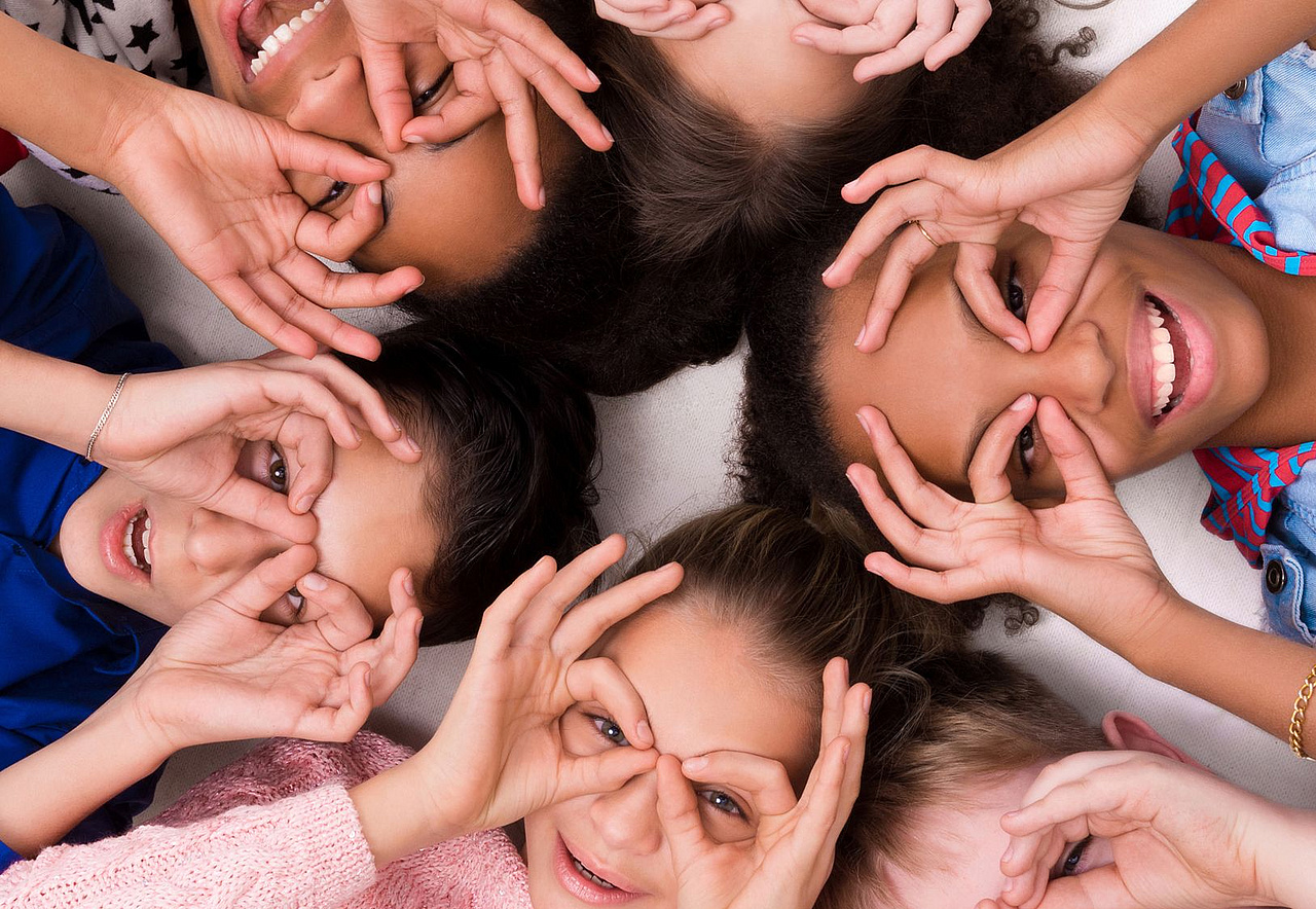 Kinder liegen im Kreis Kopf an Kopf auf dem Rücken