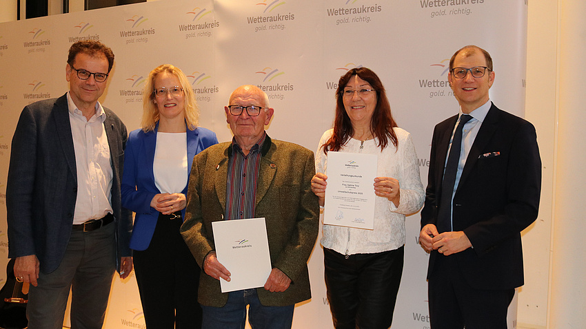 Auf dem Bild sind fünf Personen zur sehen. Sie feiern die Verleihung des Umweltschutzpreises des Wetteraukreises, die beiden Preisträger stehen in der Mitte und halten ihre Urkunden in der Hand.