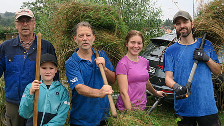 Dietmar Wäß mit zwei Erwachsen und zwei Kindern beim Heu holen