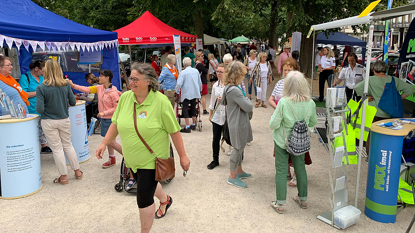 An zahlreichen Ständen stehen Menschen.