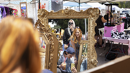 Drei junge Menschen auf einem Flohmarkt fotografieren ihr Spiegelbild