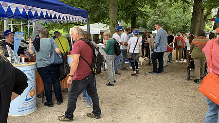 Menschen auf einem Platz, auf dem Infostände aufgebaut sind.