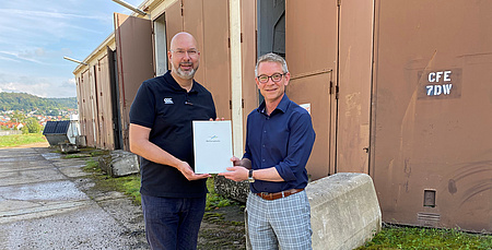 Zwei Männer halten gemeinsam eine Akte in der Hand.