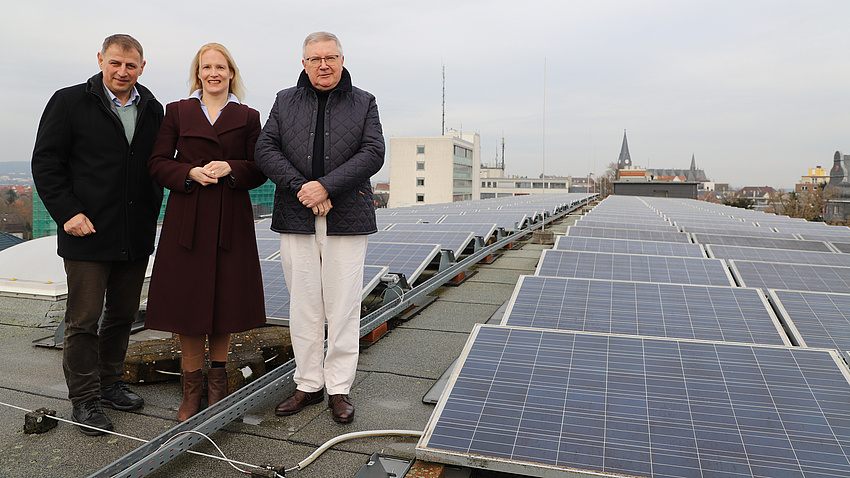 Drei Personen vor Photovoltaikanlagen.