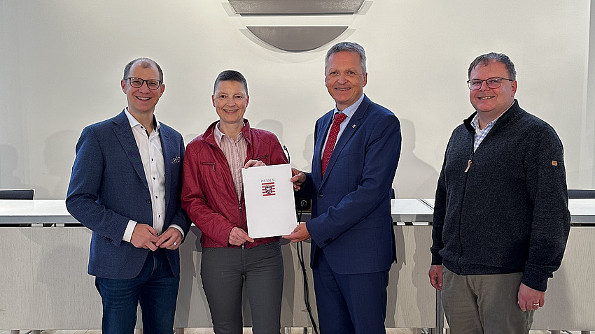 Staatssekretär Martin Rößler, Landrat Jan Weckler, Kreisbeigeordnete Marion Götz und Fachdienstleiter Jürgen Nickel halten ein Dokument in die Kamera.