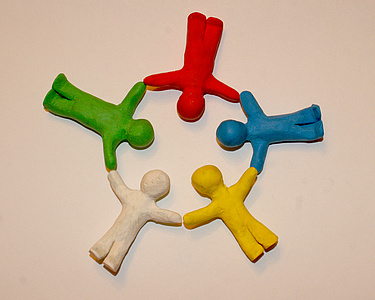 4 Knet-Menschen liegen auf dem Boden und halten sich an den Händen, bilden somit einen Kreis, Bildquelle S.Hofschläger/Pixelio.de