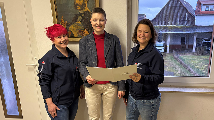 Marion Götz übergibt den Förderbescheid an Bereitschaftsleiterin Sina Dietz und Vereinsvorsitzende Christina Paulencu.