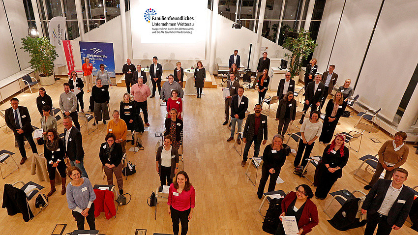 Blick von oben auf eine größere Personengruppe, die im Plenarsaal der Kreisverwaltung steht. Alle Menschen sehen nach oben zu der Person, die das Foto macht.